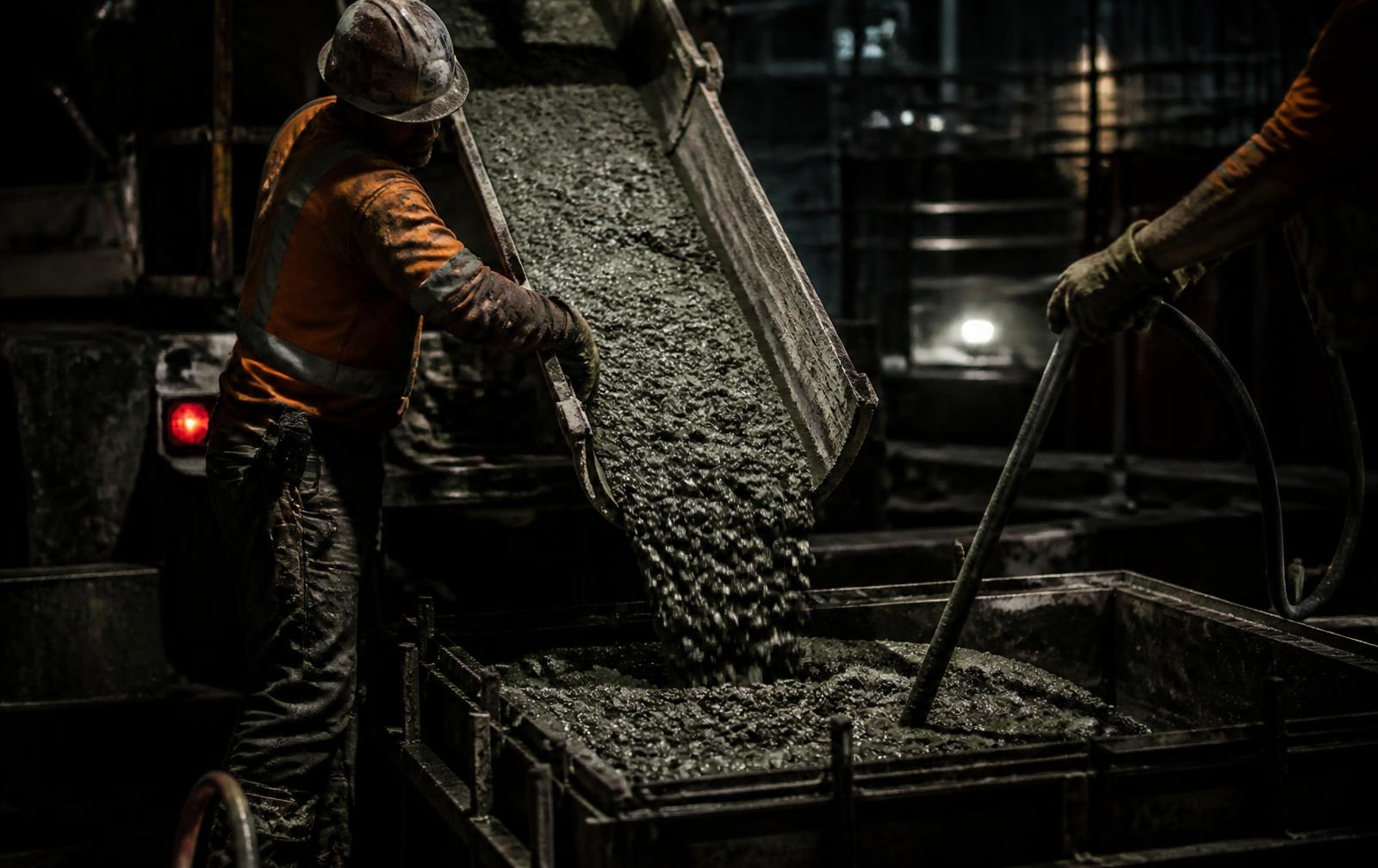Concreto sendo lançado em fôrma com operário orientando a calha